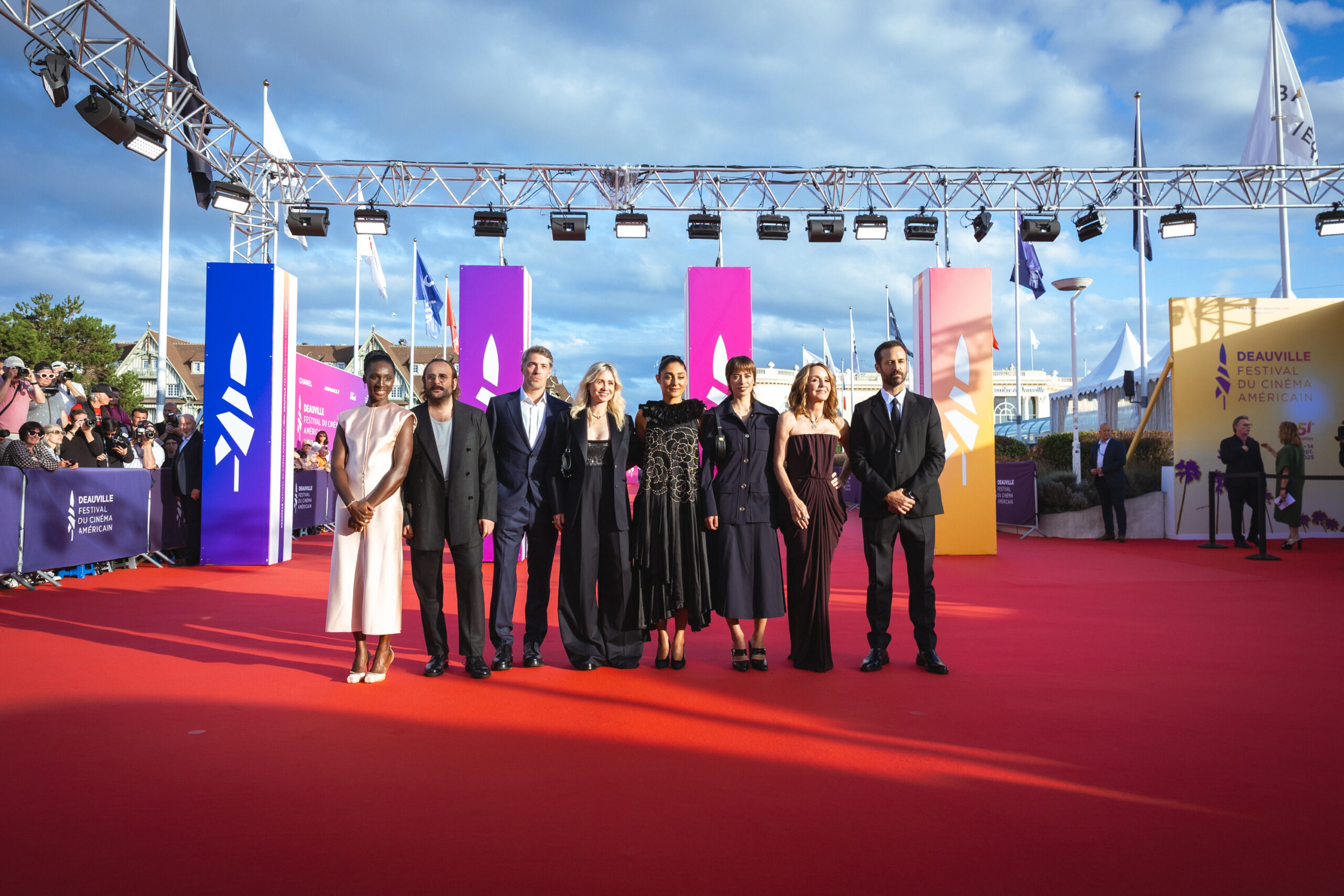 Group of elegantly dressed people posing on red carpet at Deauville American Film Festival