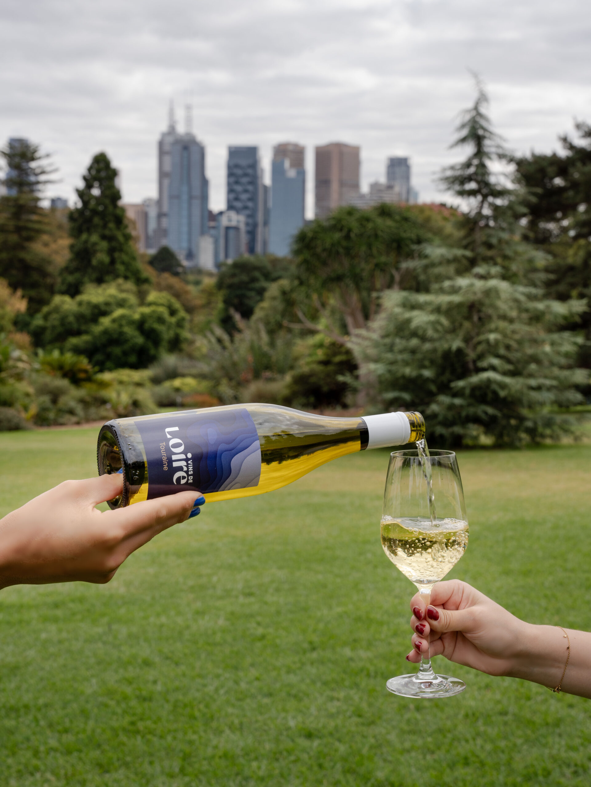 white wine being poured in front of Melbourne skyline