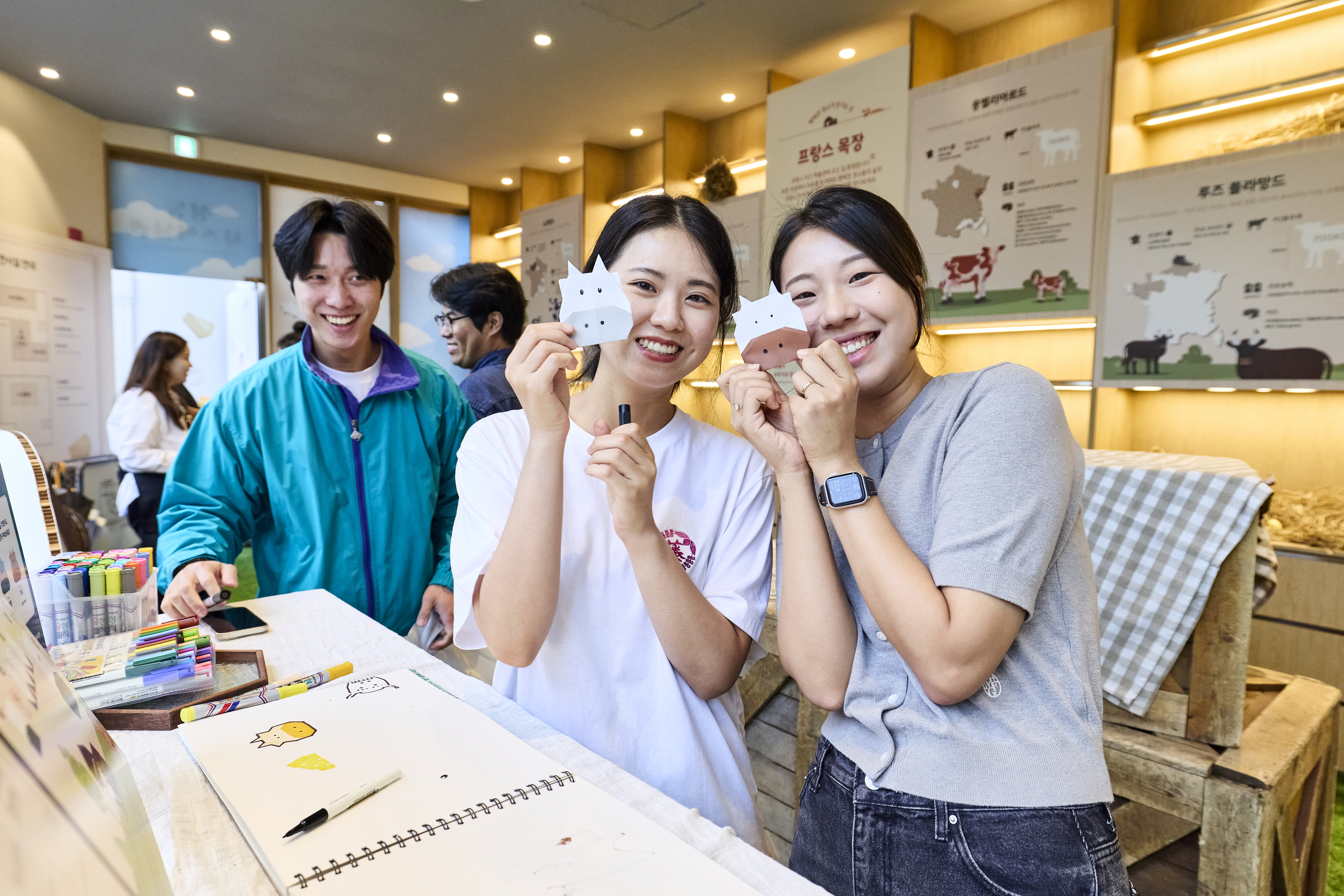 Two women showing their papermade cows to the camera at an cheese event