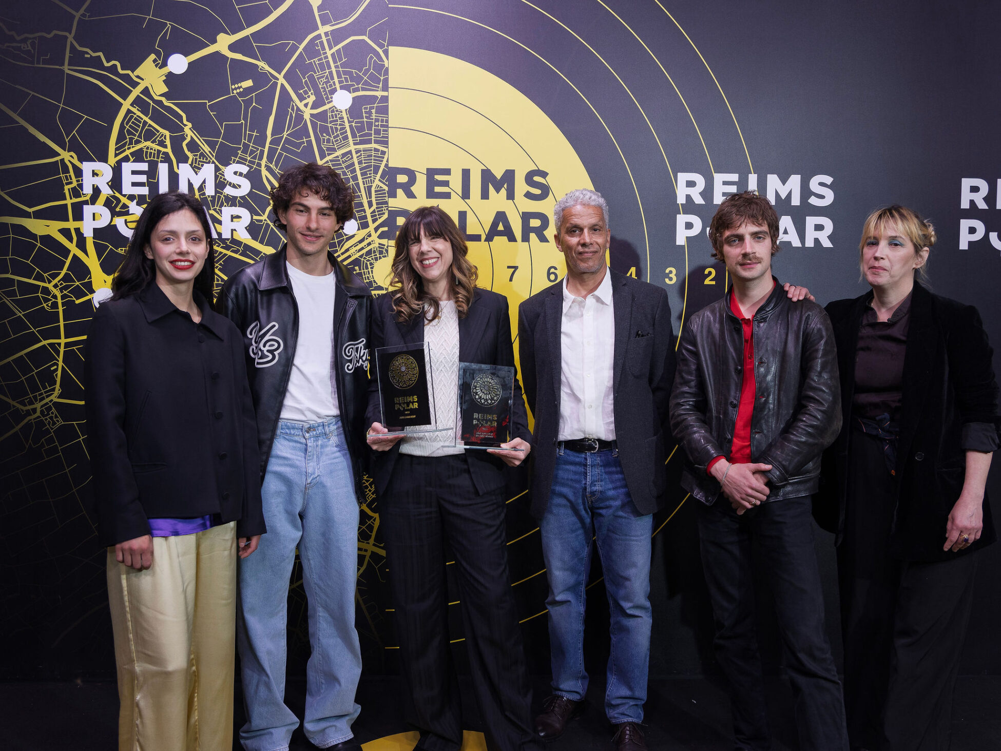 Group of seven people standing in front of Reims Polar Festival backdrop, one holding awards