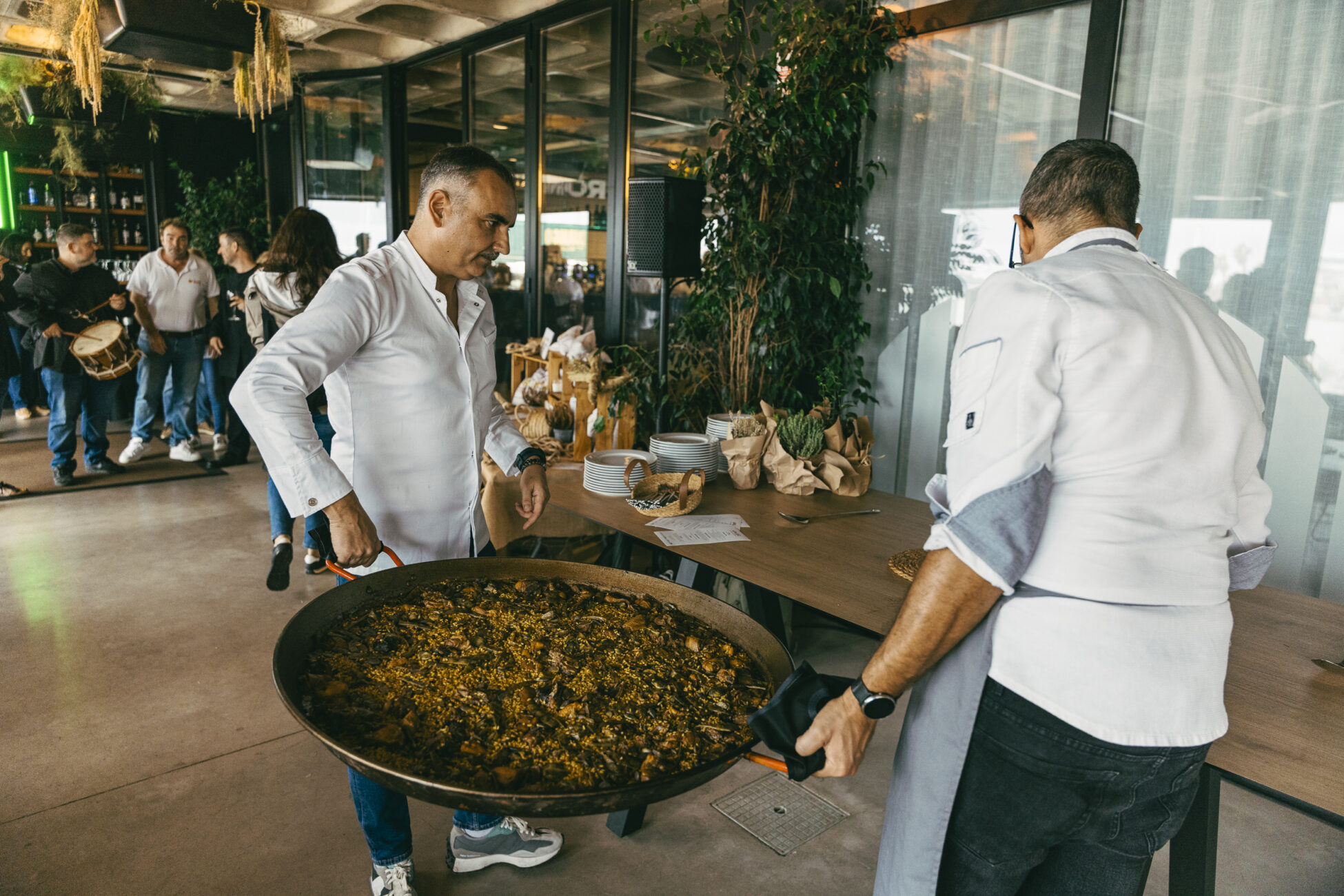 two men holding big paella