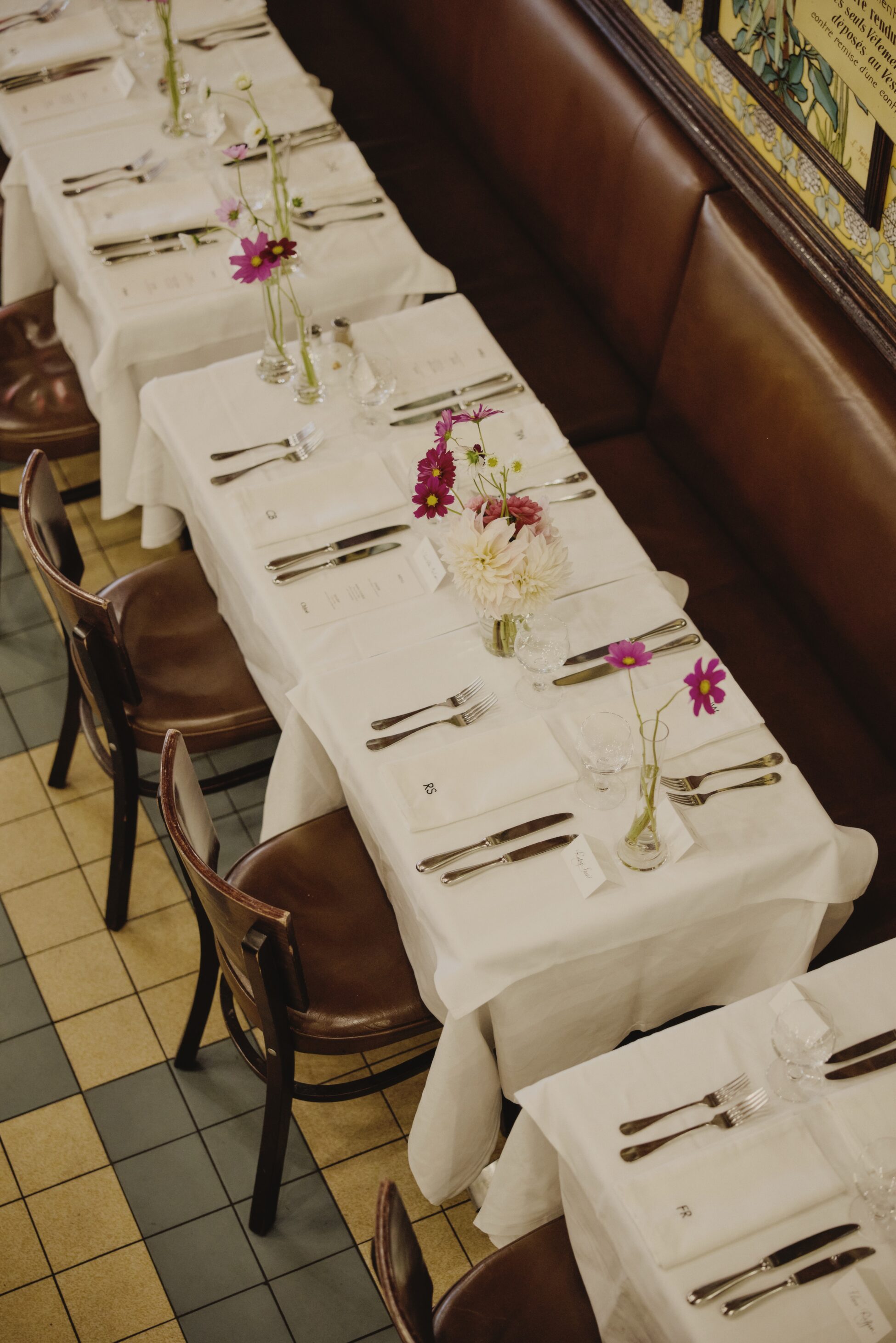 Elegant restaurant table setting with white tablecloths, floral centerpieces, and neatly arranged cutlery