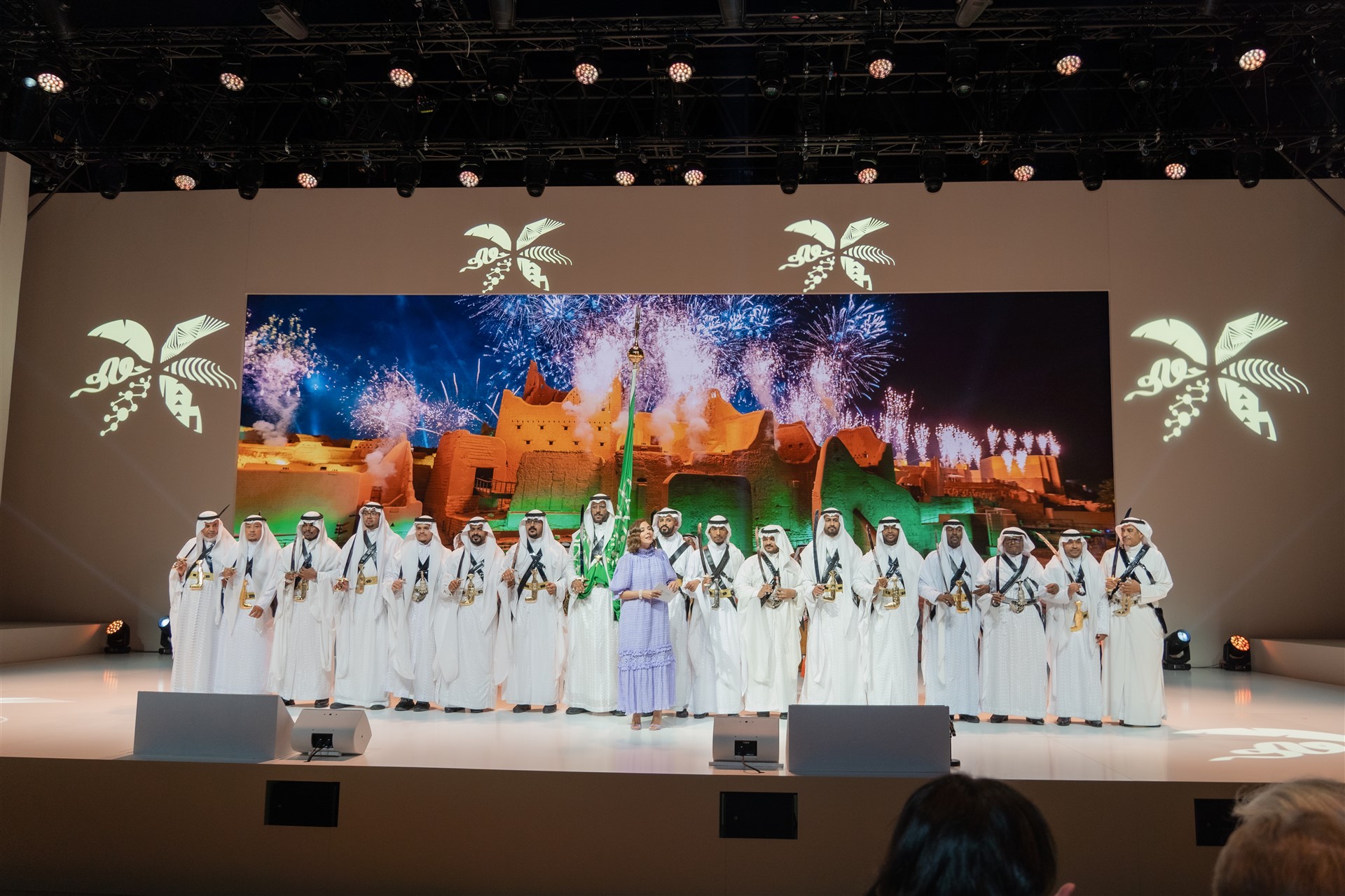 men on stage in white traditional clothing standing together